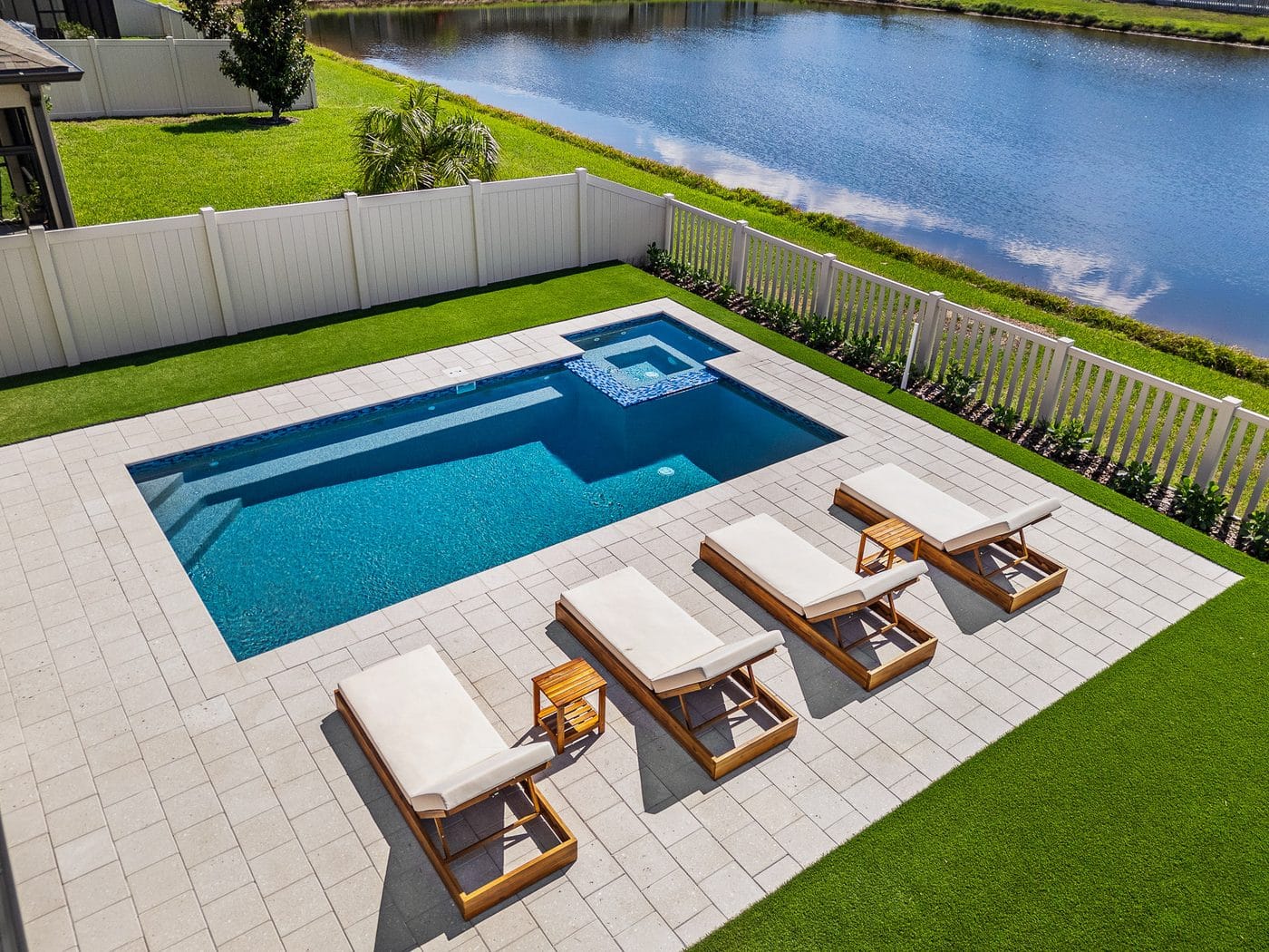 Aerial view of a Pool Perfection rectangular pool and spa overlooking a lake with lounge seating