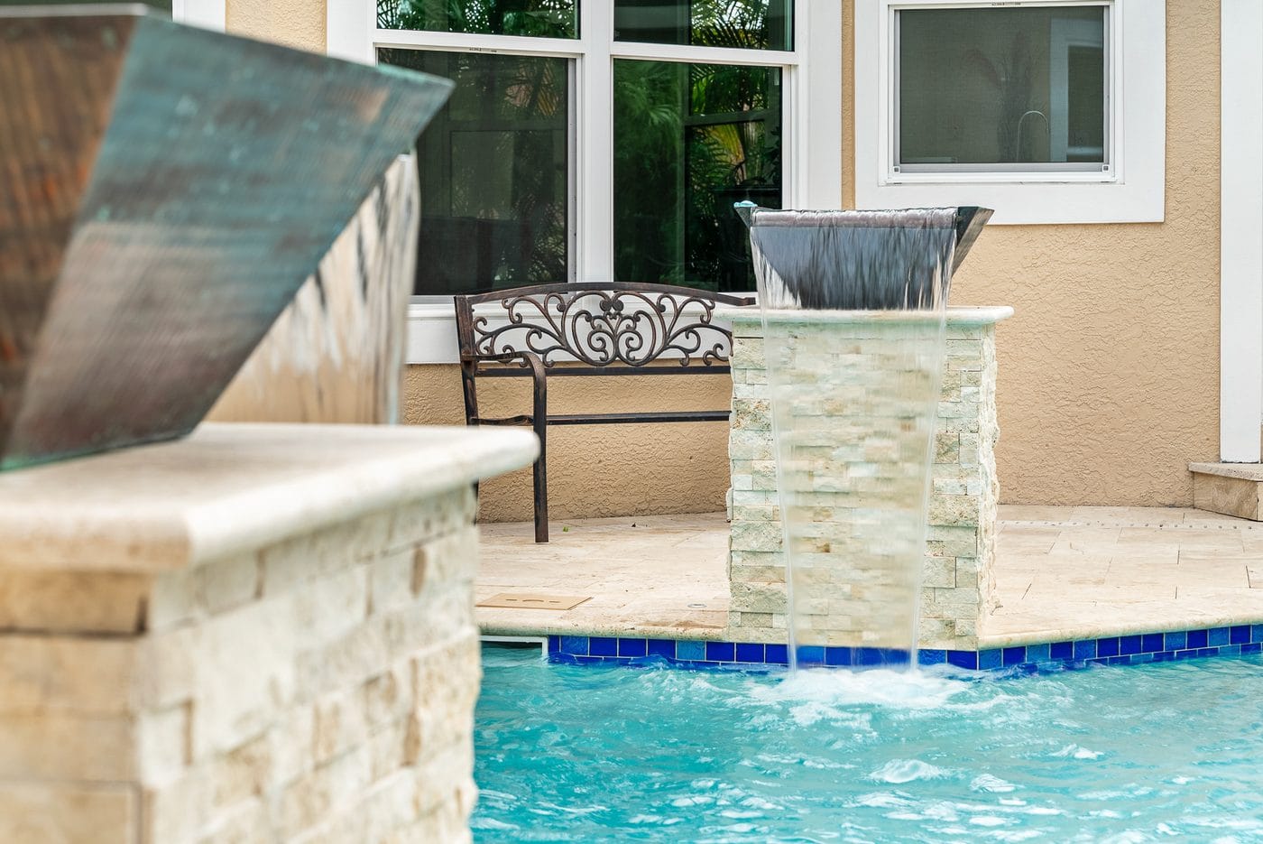 A Pool Perfection freeform pool with a natural rock grotto waterfall on a waterfront property